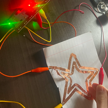 Testing two separate copper tape paths on the same sheet, each connected to a different clip, exploring whether two distinct inputs can be triggered independently.
