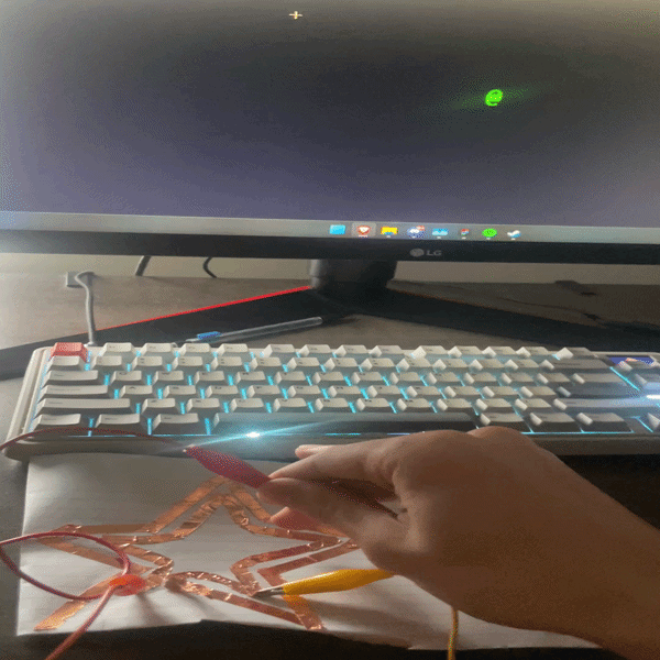 Testing a copper tape star shape as a single continuous conductive surface, touching different points of the star to see if the shape allows consistent circuit completion.